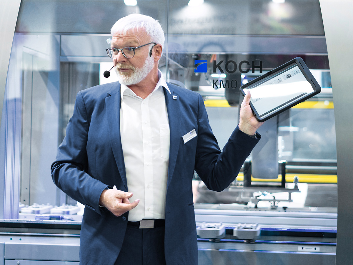 KOCH employee presenting the digital interface of the modular KMO packaging machine on a tablet